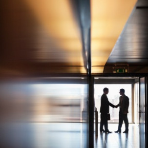 Photo of men shaking hands in silhouette.